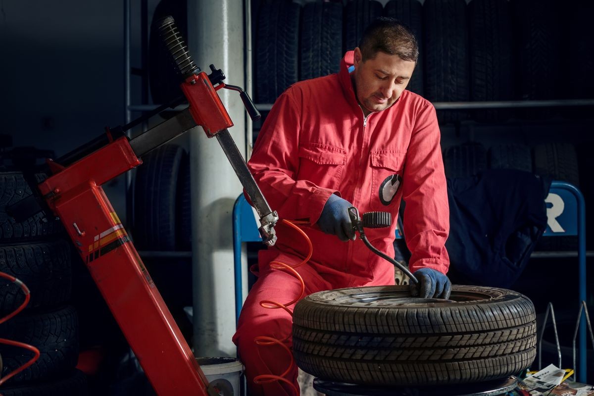 mechanic replace tyre on wheel in workshop